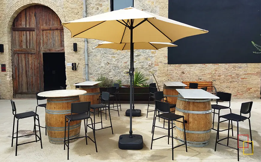 Terraza exterior del restaurante La Bodega con barricas convertidas en mesas altas