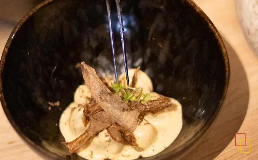 Patatas con mantequilla, miso y trufa servidas en vajilla artesanal