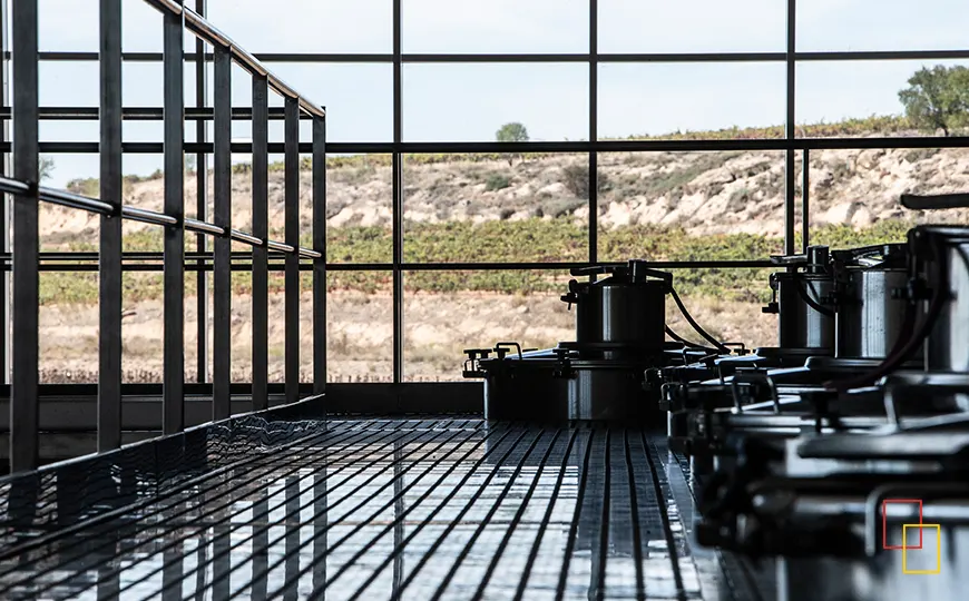 Interior de la bodega Dominio Lubiano con depósitos de acero inoxidable y vistas al viñedo a través de grandes ventanales