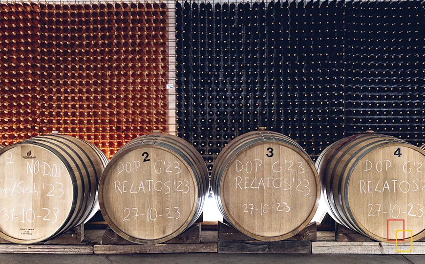 Sala de barricas en Huellas del Tiétar con toneles alineados y botellero al fondo