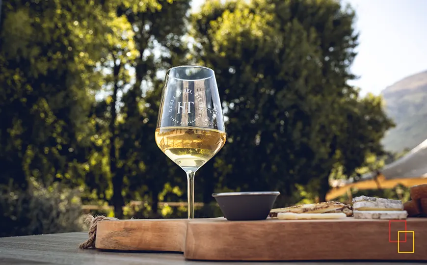 Pareja brindando con vino blanco en la terraza de Huellas del Tiétar con montañas de Gredos al fondo