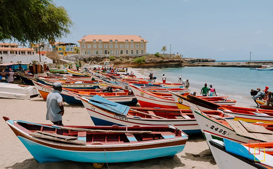 Mujeres y hombres limpiando pescado junto a las barcas en Tarrafal