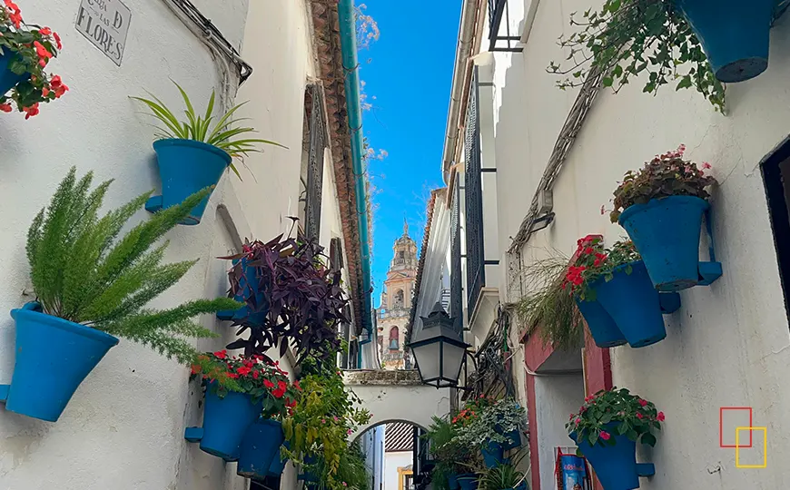 Calleja de las Flores en Córdoba con macetas azules y la torre de la Mezquita-Catedral al fondo