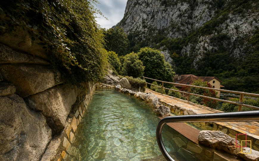 Cascada de agua termal junto a varias personas en la Cueva Termal Exterior de La Hermida