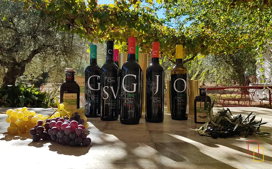 Gama de vinos ecológicos Cortijo el Cura colocados sobre una mesa con uvas y aceite de oliva