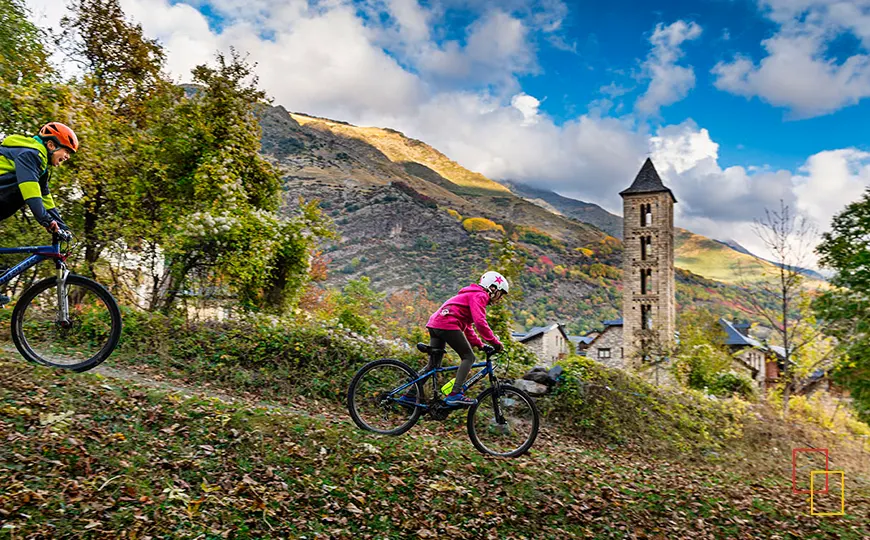 Ciclistas pedaleando entre bosque y campanario románico