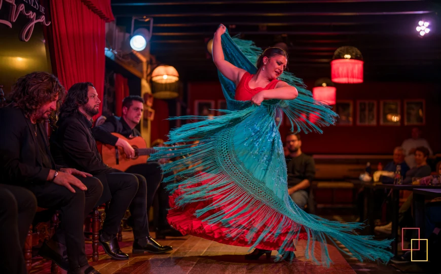 Bailaora en vestido rojo con mantón turquesa en Jardines de Zoraya, con músicos al fondo