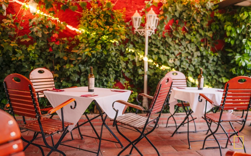 Mesas en el patio-jardín de Jardines de Zoraya con botellas de vino y vegetación