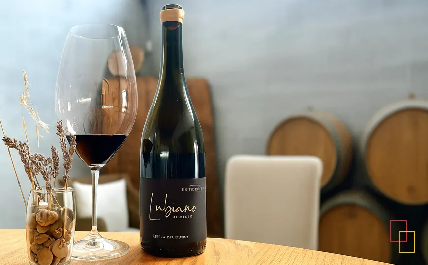 Botella de Lubiano Edición Limitada y copa de vino tinto sobre mesa de madera en el wine-bar de la bodega