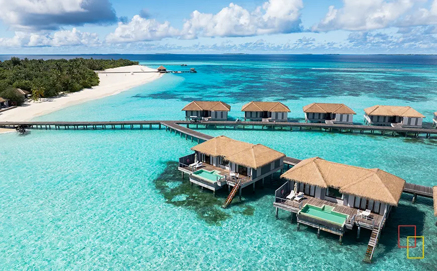 Vista aérea de un resort en Ari Atoll con laguna turquesa y pasarelas sobre el agua