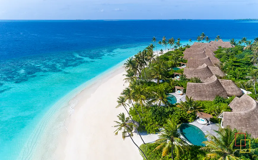 Fila de villas de playa con piscinas privadas junto a una playa de arena blanca
