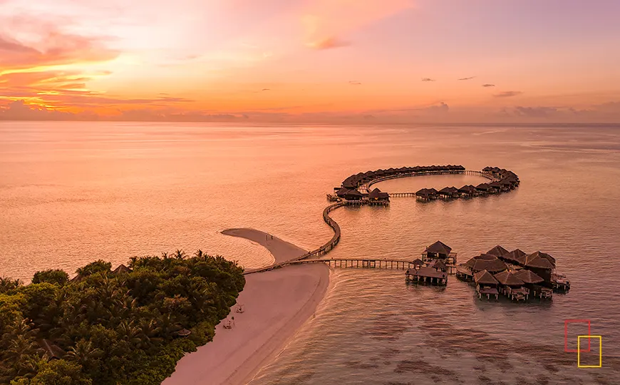 Aérea al atardecer con pasarelas circulares de villas sobre el agua en Maldivas