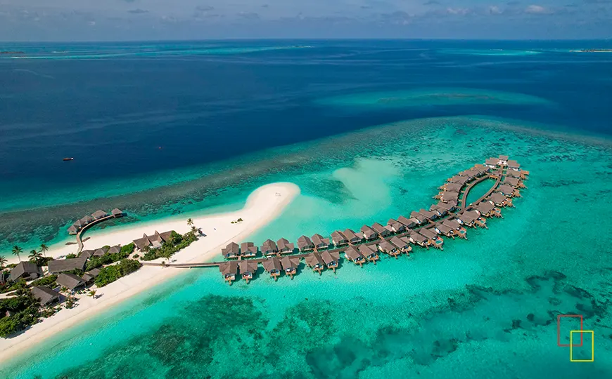 Vista aérea desde hidroavión de isla-resort con lengua de arena y villas sobre el agua