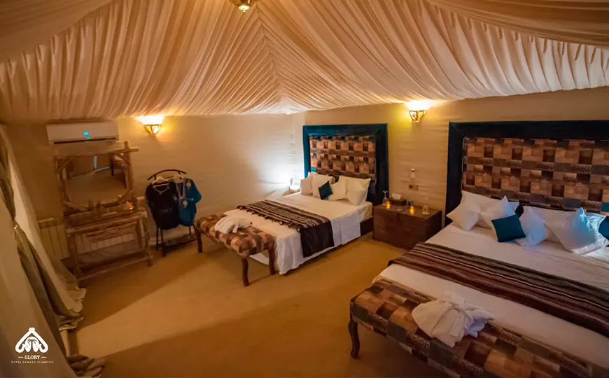 Interior de jaima tipo glamping con dos camas y lámparas artesanales