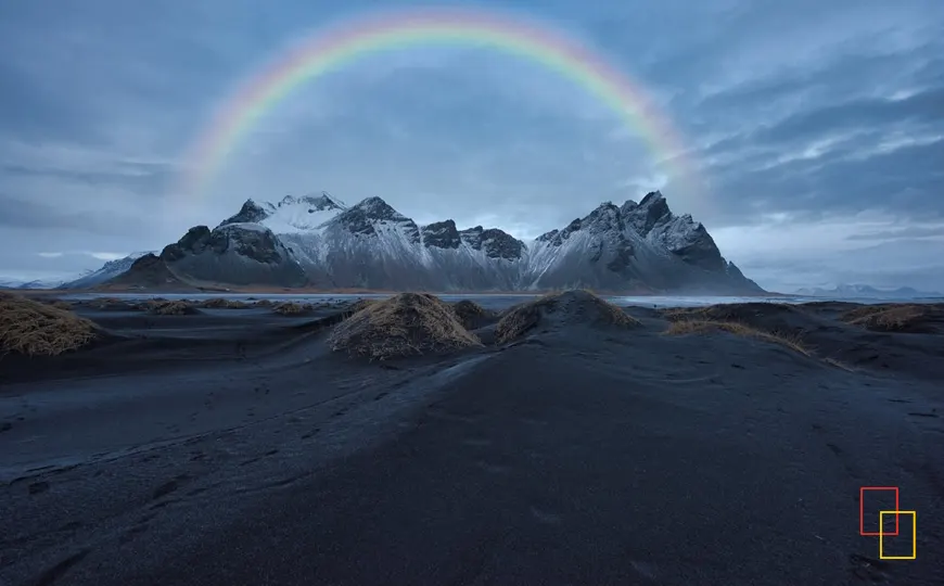 Montañas nevadas en Islandia con un arcoíris en el horizonte