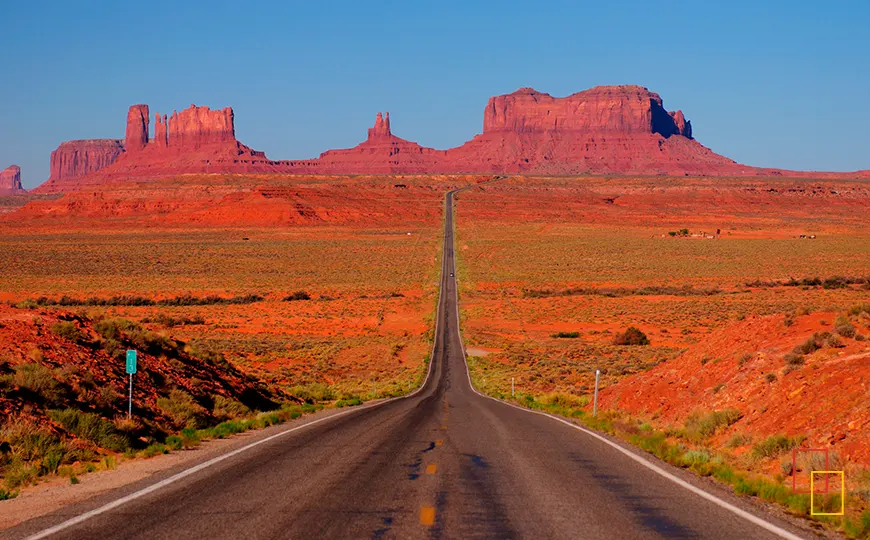 Carretera US-163 recta avanzando hacia los monolitos de Monument Valley