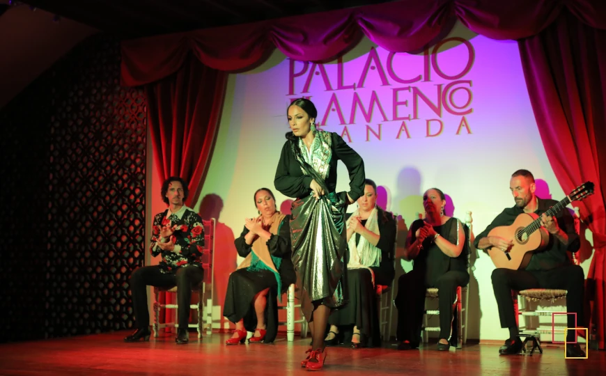 Bailaora en el escenario del Palacio Flamenco Granada, con el cuadro flamenco al fondo