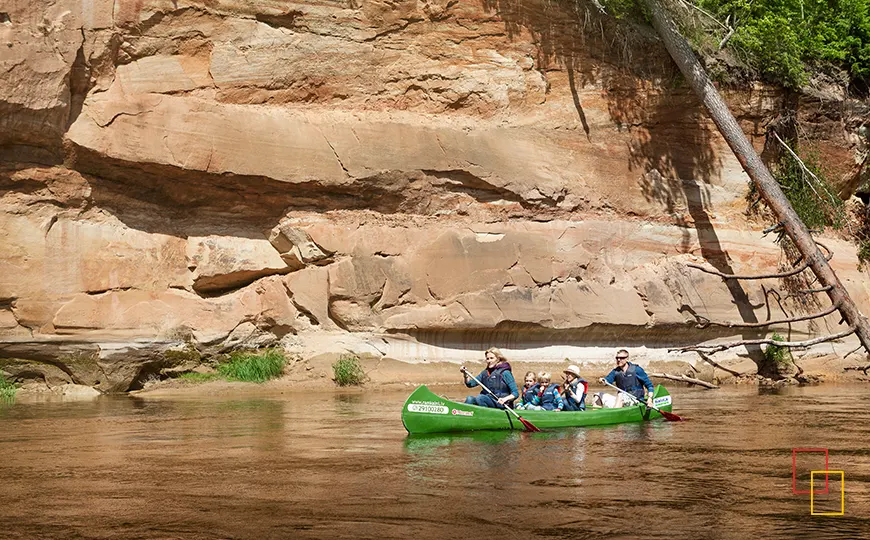 Familia remando en canoa junto a los acantilados de arenisca del río Gauja