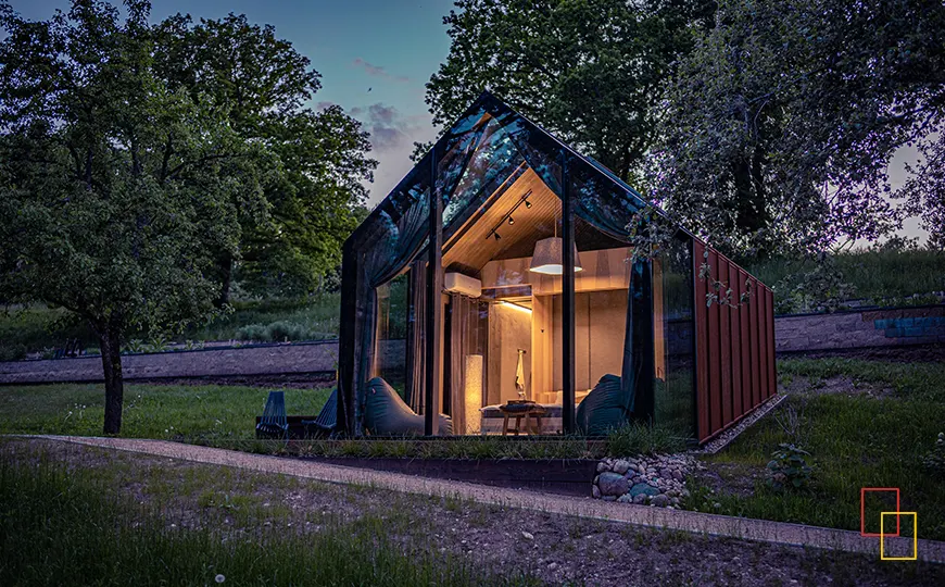 Cabaña de cristal Ziedlejas iluminada al anochecer en el Parque Nacional de Gauja