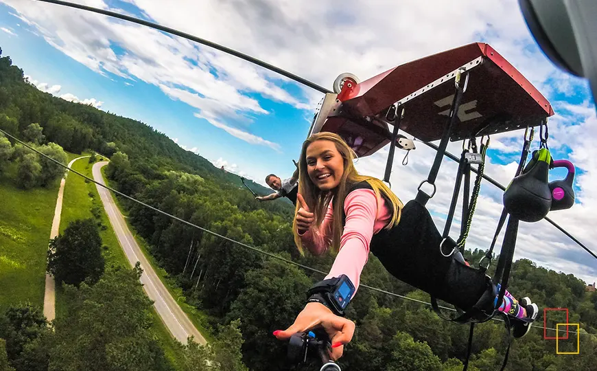Turista volando en la tirolina Zērglis sobre el valle del Gauja en Sigulda
