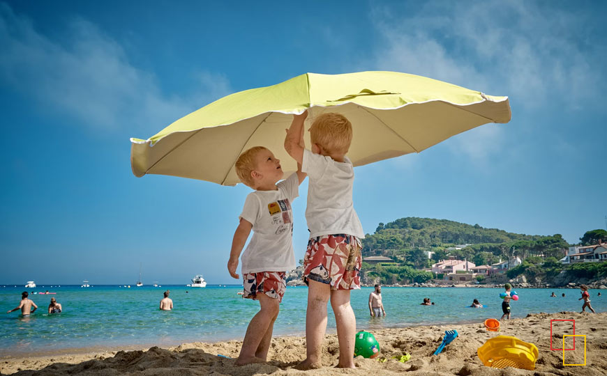 Niños jugando bajo una sombrilla en una playa