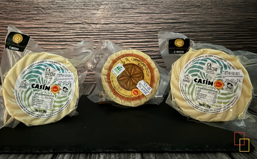 Tres piezas envasadas de Queso Casín DOP (Ca Llechi y Redes) sobre pizarra