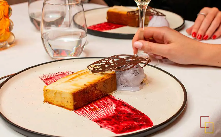 Tarta cremosa de queso gallego sobre coulis de frutos rojos, teja de chocolate negro y helado artesano de violeta
